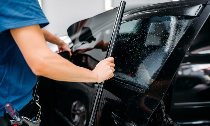 Male specialist applying car tinting film Male specialist applying car tinting film, installation process, tinted auto glass installing procedure
