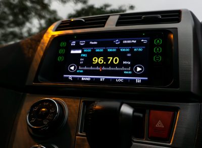 The close up view of the smart multimedia touchscreen radio panel in the car with street light flare during the rain. Car system control using panel button screen interface modern design.