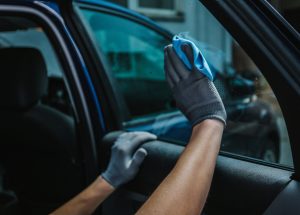 Worker cleaning car window after applying tinting foil Worker cleaning car window after applying tinting foil