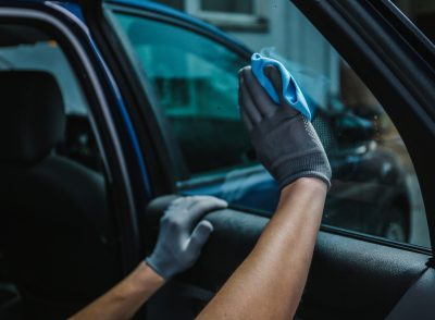 Worker cleaning car window after applying tinting foil